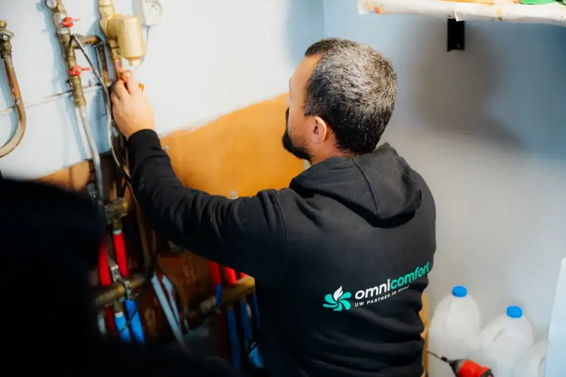 Installateur van Omnicomfort werkt aan de leidingen van een verwarmingsinstallatie