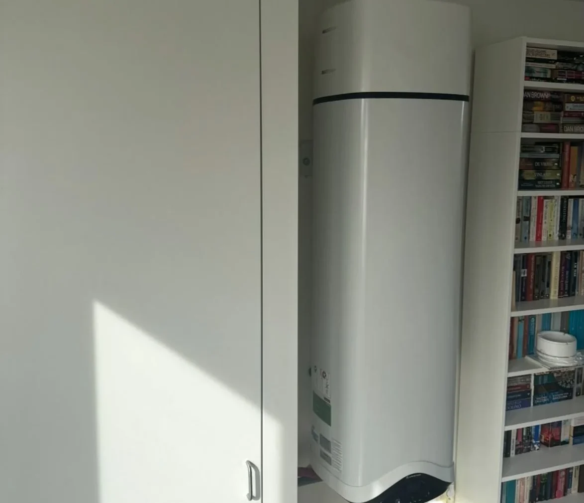 Warmtepompboiler aan de muur naast een boekenkast