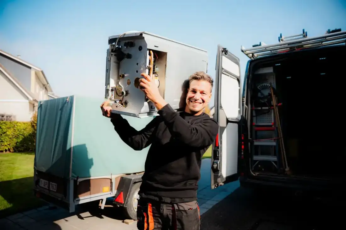Installateur van Omnicomfort draagt een oude cv-ketel naar de bestelwagen