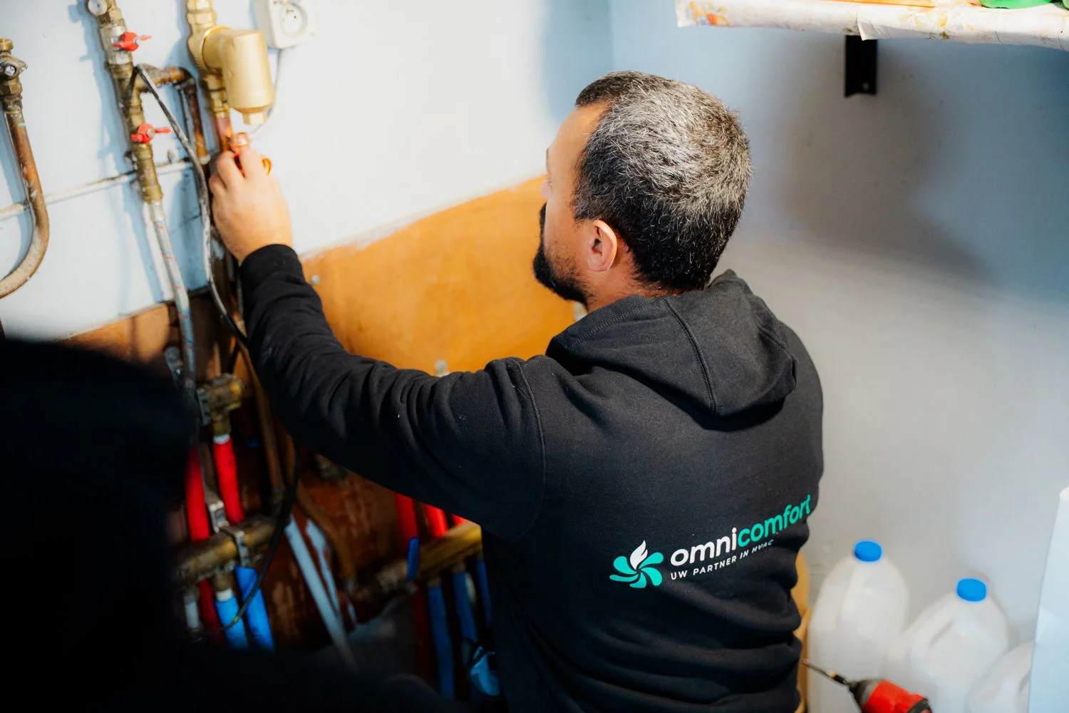 Installateur van Omnicomfort werkt aan de leidingen van een verwarmingsinstallatie