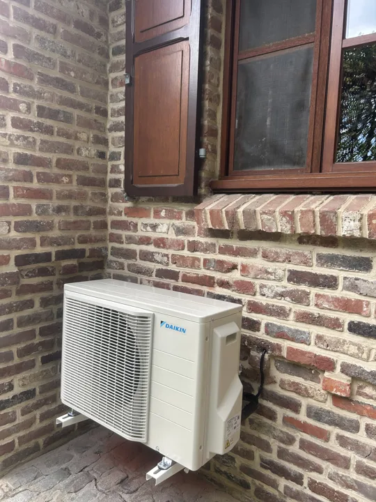Buitenunit aan een oude bakstenen muur