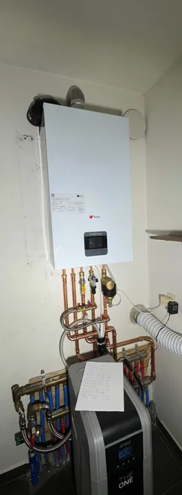 Witte cv-ketel aan de muur met koperen leidingen eronder