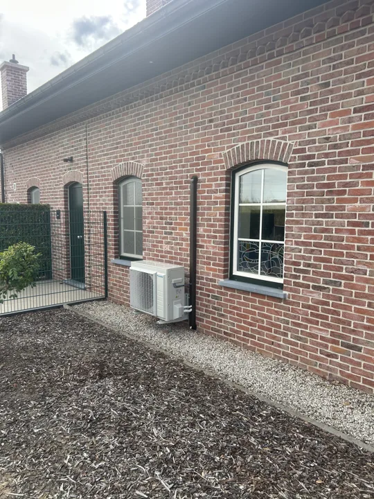 Buitenunit langs de bakstenen gevel